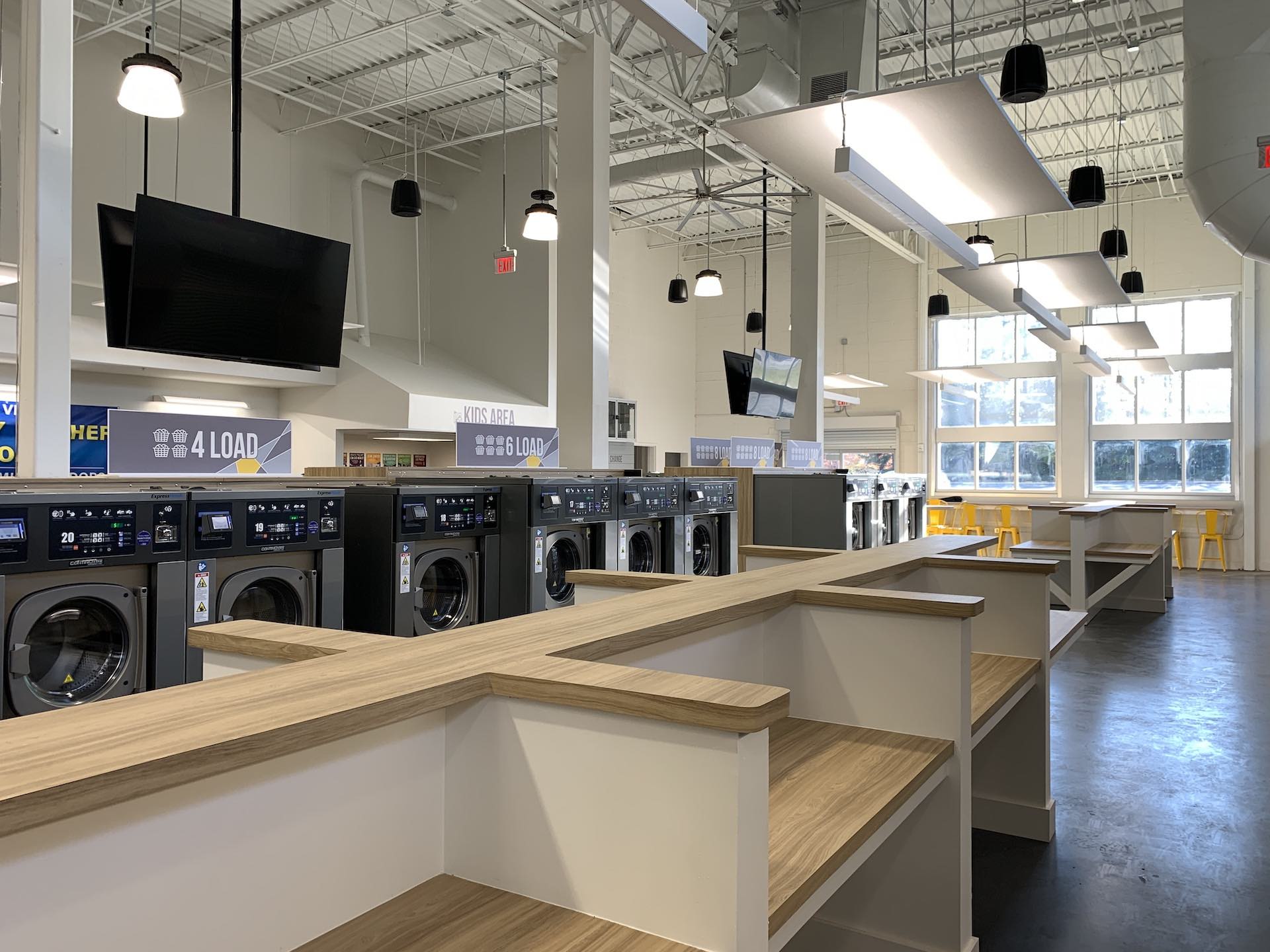 Interior of Oz Laundry with washers, folding tables and TVs