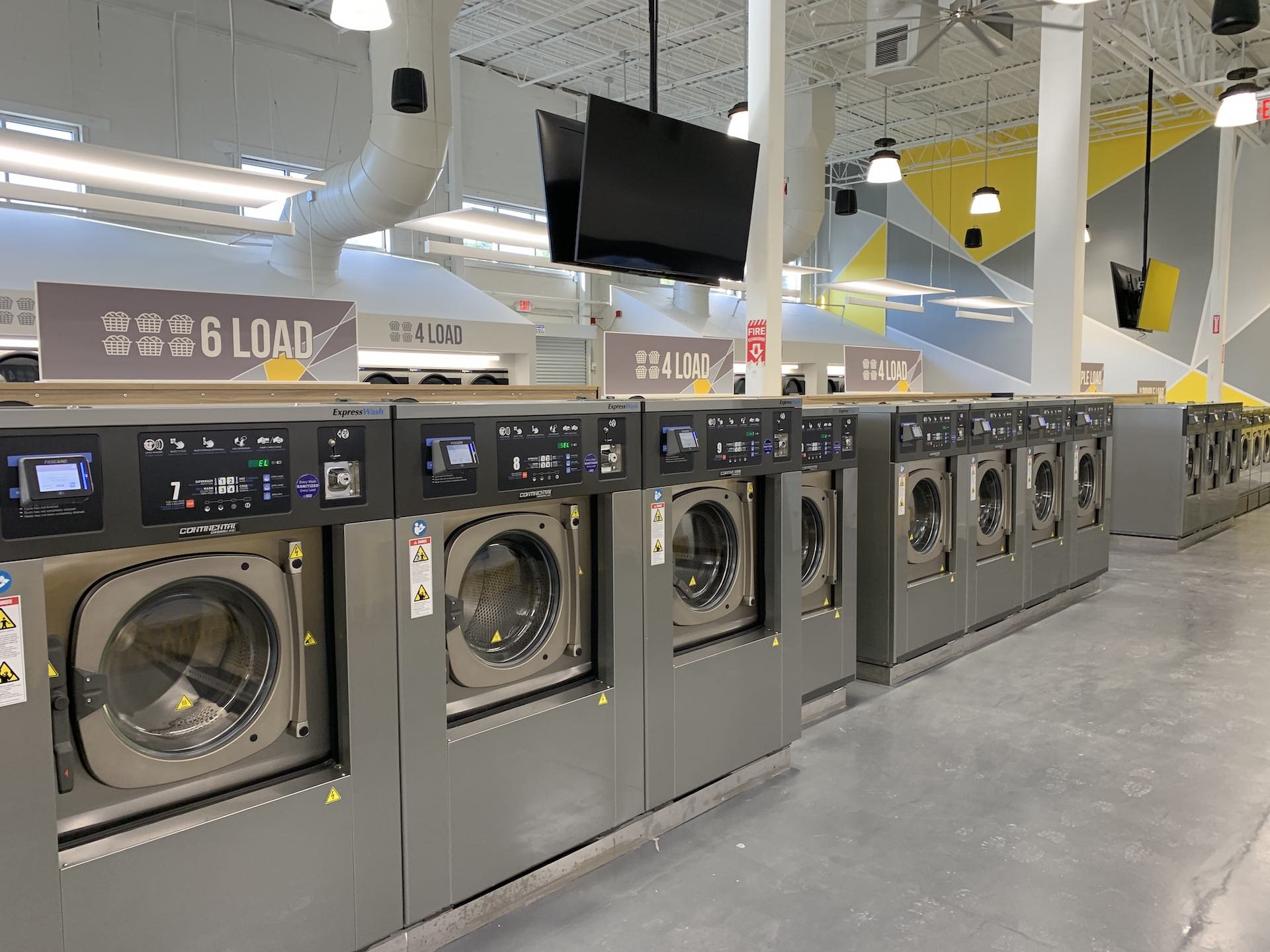 Six-load washers beneath the Oz Laundry brand wall